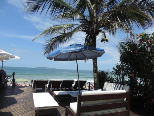 a beach with chairs and an umbrella and the ocean at Pousada Pedra da Gaivota in Bombinhas