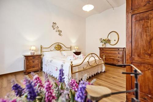 a bedroom with a bed with purple flowers in it at La Dimora degli Olivi in Torrita di Siena