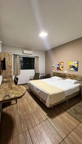 a large bedroom with a large bed and a table at Mariá Plaza Hotel in Araçatuba