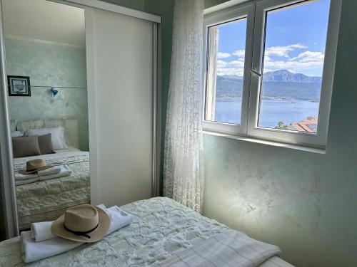a bedroom with a hat on a bed with a window at Villa Mare Apartments in Tivat