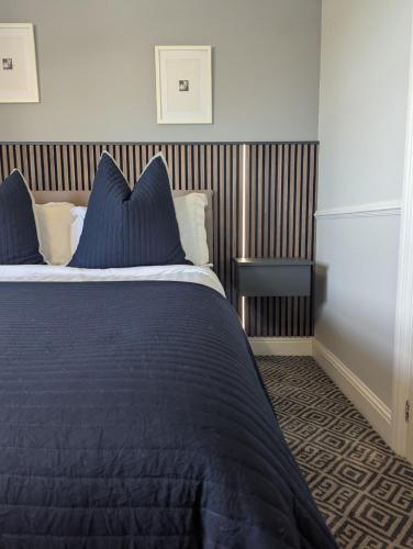 a bed with blue sheets and pillows in a bedroom at Willowbank House and Lodges in Enniskillen