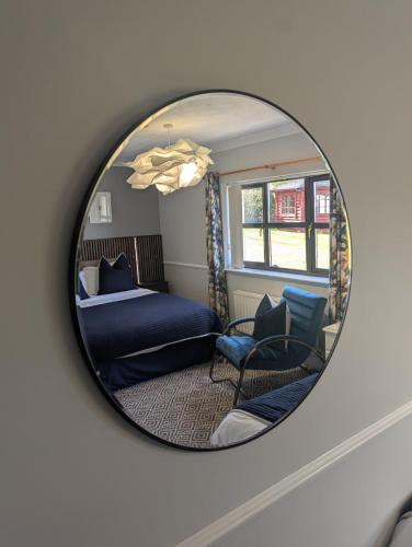 a mirror reflecting a bedroom with a bed and chairs at Willowbank House and Lodges in Enniskillen