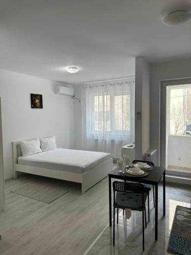a white bedroom with a bed and a table at Apartment complex in Roşu