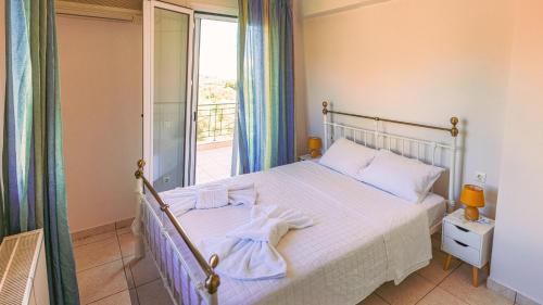 a bedroom with a bed with white sheets and a window at Villa Rodothea in Khelmáta