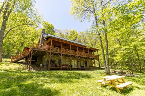 a large log cabin in the woods with a picnic table at A Beary Good Time in Boone