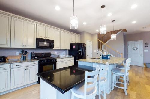 a kitchen with white cabinets and a island with bar stools at Bishops Landing -- 16985 Bellevue in Millville