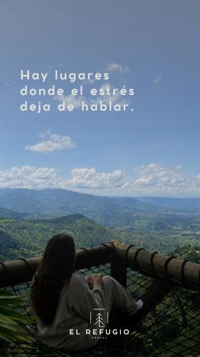 a woman sitting on the edge of a tower looking at the mountains at Cabaña el Refugio Buenavista in Buenavista