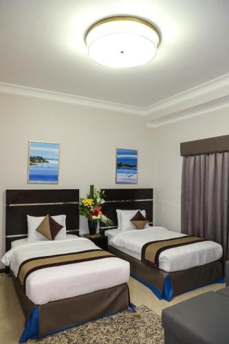 a hotel room with two beds and a light at Ruru Tower Luxury Apartment in Juffair