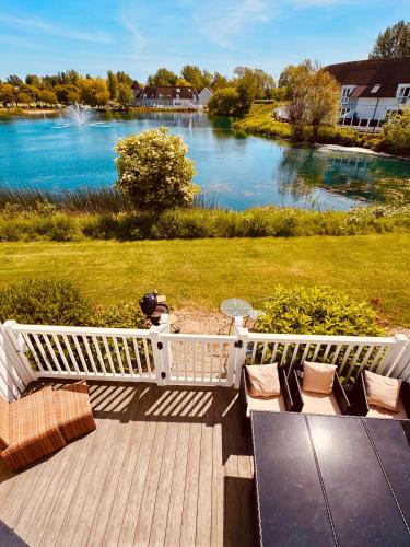 a wooden deck with chairs and a view of a river at Barneys Retreat - Lakeside Getaway in South Cerney