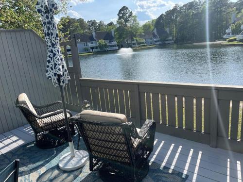 two chairs and an umbrella on a deck next to a lake at Sea Colony West Pine in Bethany Beach