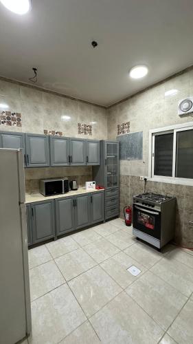 a kitchen with gray cabinets and a stove at شقق ابو طلال المفروشة in Sakakah
