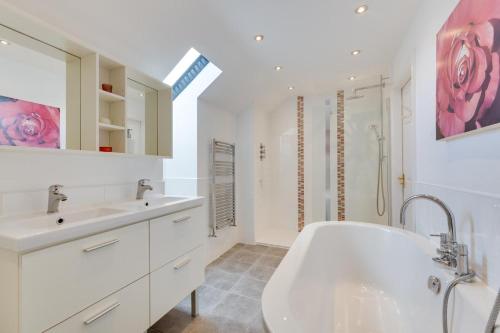 a white bathroom with a tub and a sink at Moo House in Beadnell
