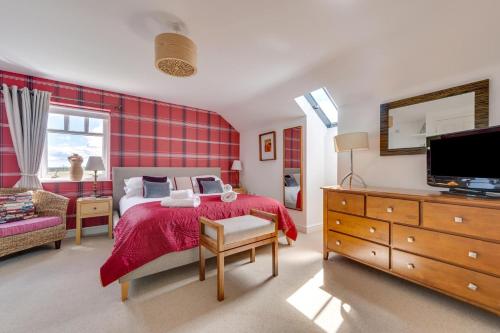a bedroom with a bed and a tv and a dresser at Moo House in Beadnell