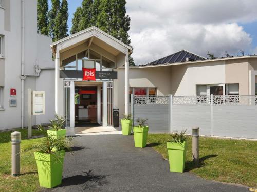 a building with green potted plants in front of it at Ibis Le Havre Sud Harfleur in Harfleur