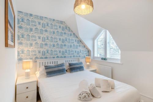 a bedroom with a white bed with blue pillows at Smugglers Hide in Beadnell