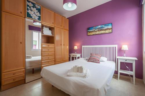 a bedroom with purple walls and a bed with towels at Salado Apartment in Seville