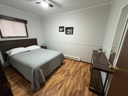 a bedroom with a bed and a wooden floor at Lush's Cottages in Cormack