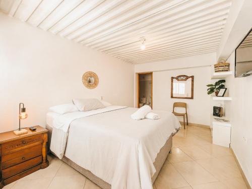 a white bedroom with two beds and a table at La Jaus by Hope in Guatapé