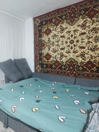 a bed in a room with a rug on the wall at Алима in Ottuk