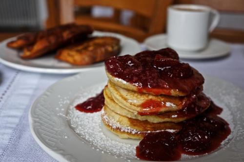 a stack of pancakes with jam on a white plate at Saxonis Houses & Saxonis Villa in Papigko