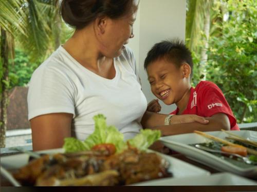 a woman and a child sitting at a table with a plate of food at Eden House Ubud in Ubud