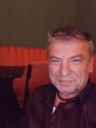 a man sitting in an orange chair smiling at the camera at Tepelen Albania in Tepelenë