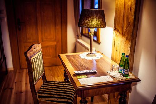 a wooden table with a lamp and a chair with a lamp at Pensjonat Dom Zegarmistrza in Bogatynia