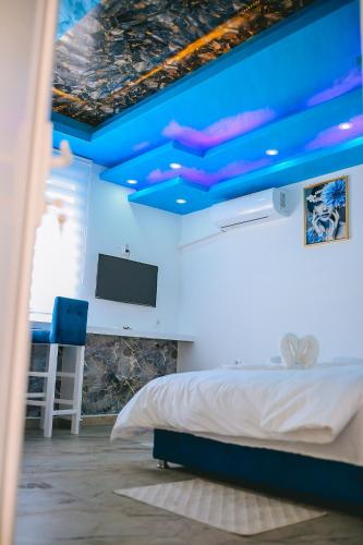 a bedroom with blue ceilings and a bed and a tv at Lux apartmani Savić in Aleksinac
