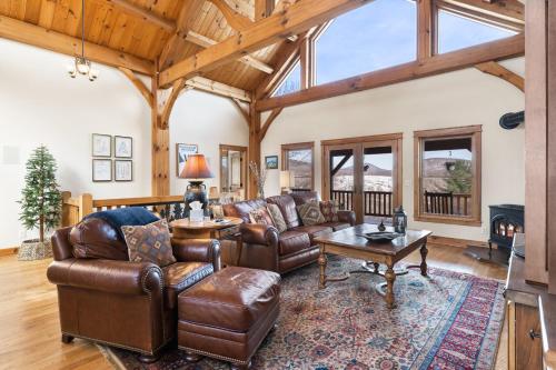 a living room with leather furniture and a wooden ceiling at Wolf Ridge Lodge in Boone