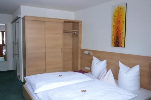 a bedroom with a white bed with a wooden headboard at Hotel Garni Sport Sonneck in Galtür