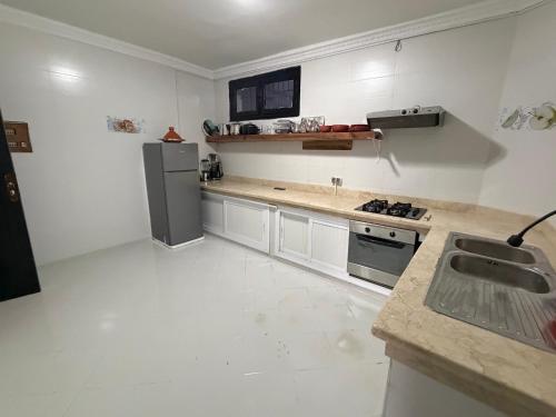a white kitchen with a sink and a refrigerator at Soumaya plage appartement in Fnidek