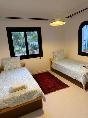 a bedroom with two beds and two windows at Soumaya plage appartement in Fnidek