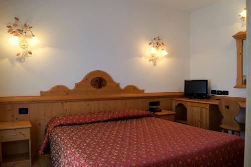 a bedroom with a bed with a red bedspread and a tv at Hotel Milano in Asiago