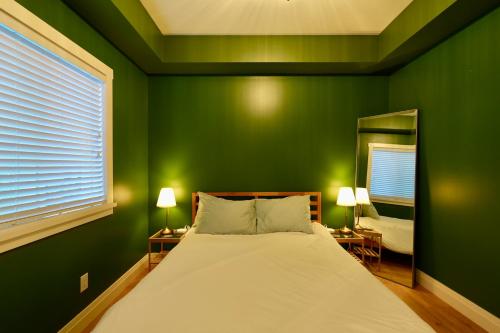 ein grünes Schlafzimmer mit Bett und Spiegel in der Unterkunft Dornier Main in Victoria