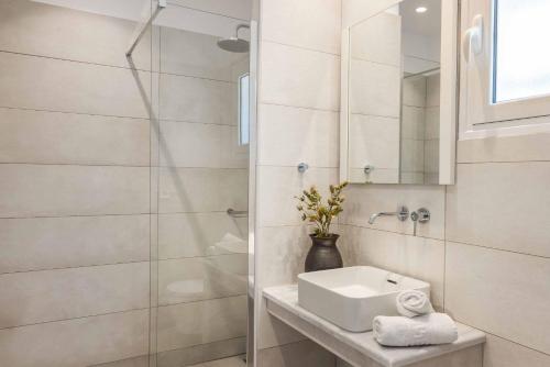 a white bathroom with a sink and a shower at Villa Mihas in Vlachata
