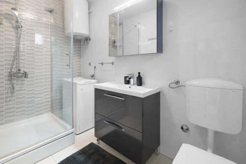 a white bathroom with a sink and a shower at Apartmani Rialto in Kakma