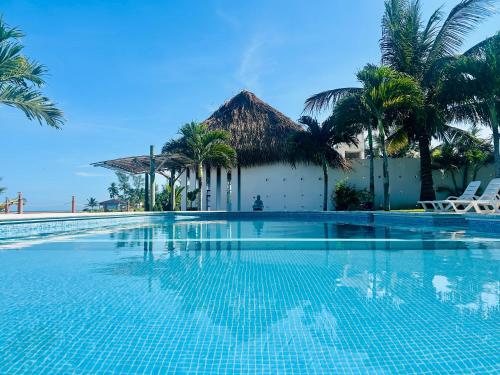 a swimming pool in front of a building with palm trees at Hotel Lunazul In Costa Esmeralda in La Vigueta