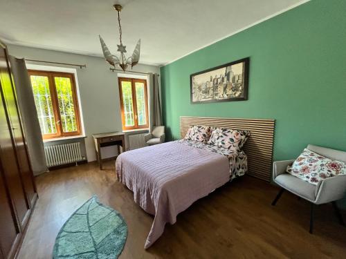 ein Schlafzimmer mit grünen Wänden, einem Bett und einem Stuhl in der Unterkunft Giulia Cottage in Strona