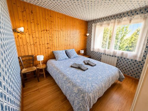 a bedroom with a bed with a blue blanket and a window at Chalet SOL LA MI in Soultzeren