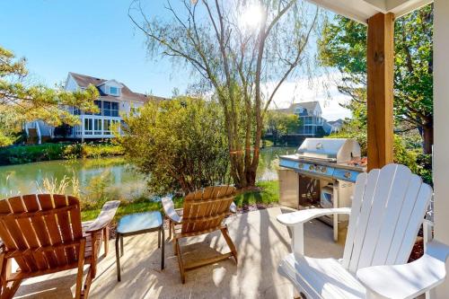 a patio with chairs and a grill and a river at Sea Colony - 56032 Great Pine in Bethany Beach