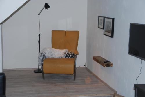 a living room with a chair and a television at De Hagmolenbeek Boekelo in Boekelo