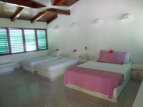 a white room with two beds and two windows at BeachCasaDonPepe in Barra de Potosi