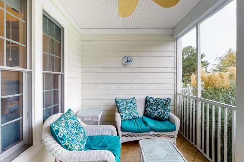 a screened in porch with two chairs with blue pillows at Bear Trap Dunes - 91 Willow Oak in Ocean View