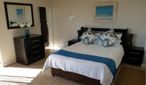 a bedroom with a bed with a vase of flowers on it at Beach Apartment Melkbosstrand in Melkbosstrand