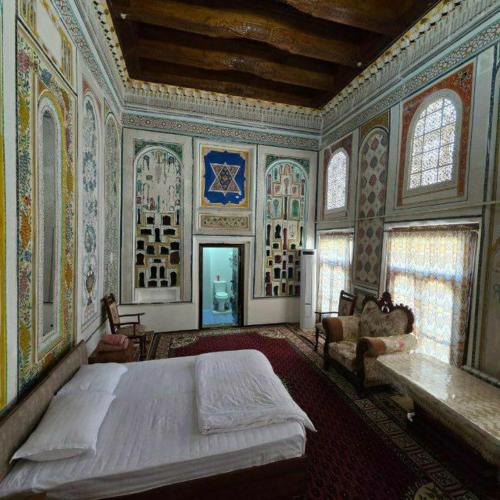a bedroom with a large bed in a room with paintings at Mekhtarin in Bukhara