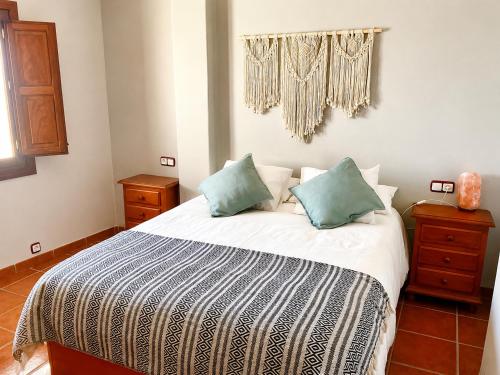a bedroom with a bed with two blue pillows at Capileira Luz de Sierra in Capileira