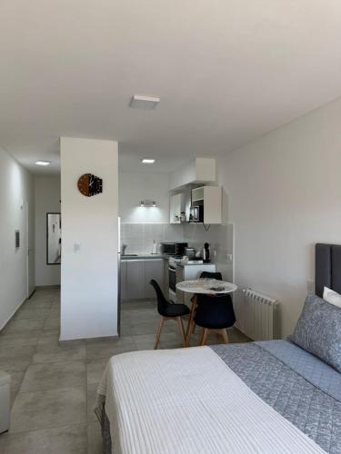 a bedroom with a bed and a table and a kitchen at Bienestar Studio in Bahía Blanca