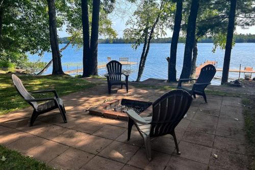 four chairs sitting around a fire pit by the water at Pair-a-Docks Landing in Minocqua
