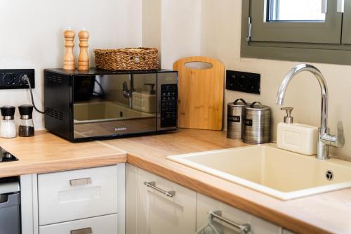 a kitchen counter with a microwave and a sink at Olea White in Skiathos