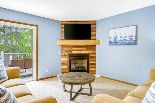 a living room with a fireplace and a flat screen tv at Road Lake Escape in Tomahawk